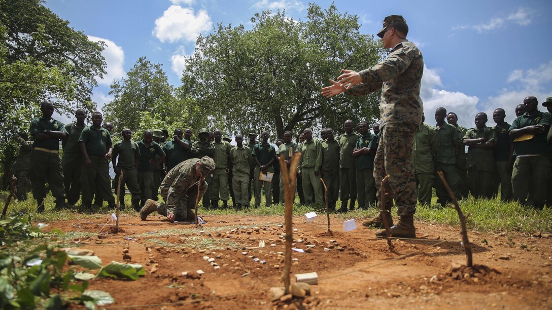 U.S. Marine Sgt. Kyle Kimbriel, right, displays a terrain model to Tanzanian park rangers as Cpl. Joseph Kakascik, center, places a tactical control measure onto the model at the Selous Game Reserve in Matambwe Tanzania, March 9, 2015. Kimbriel is the noncommissioned officer in charge of Theater Security Cooperation team with Special-Purpose Marine Air-Ground Task Force Crisis Response-Africa, and Kakascik is a rifleman and squad advisor assigned to the unit. More than 15 Marines with SPMAGTF-CR-AF helped teach the park rangers mission analysis, order writing and land navigation skills.