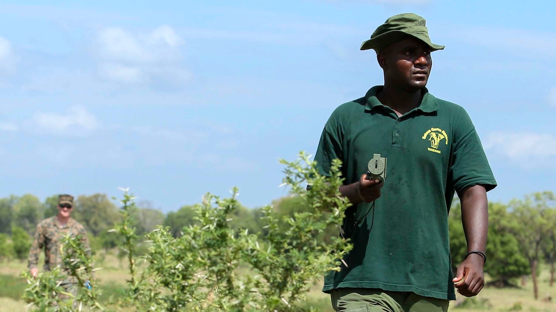 A Tanzanian park ranger uses a compass to find an objective as U.S. Marine Cpl. William Spahr, rear, a machine gunner assigned to the Theater Security Cooperation Team with Special-Purpose Marine Air-Ground Task Force Crisis Response-Africa, supervises during a simulated reconnaissance patrol and land navigation exercise at the Selous Game Reserve in Matambwe, Tanzania, March 11, 2015. Approximately 15 Marines and Sailors taught more than 40 park rangers mission analysis, order writing and land navigation skills. (U.S. Marine Corps photo by Lance Cpl. Lucas J. Hopkins/Released)