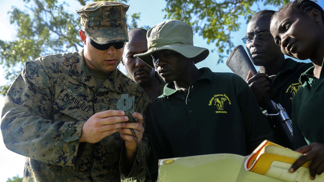 U.S. Marine Lance Cpl. Kyle McAuliffe, a rifleman and squad advisor assigned to the Theater Security Cooperation team with Special-Purpose Marine Air-Ground Task Force Crisis Response-Africa, helps a team of Tanzanian park rangers shoot an azimuth on a compass before conducting a simulated reconnaissance patrol and land navigation exercise at the Selous Game Reserve in Matambwe, Tanzania, March 11, 2015. McAuliffe was one of approximately 15 Marines and Sailors teaching the park rangers mission analysis, order writing, and land navigation skills.