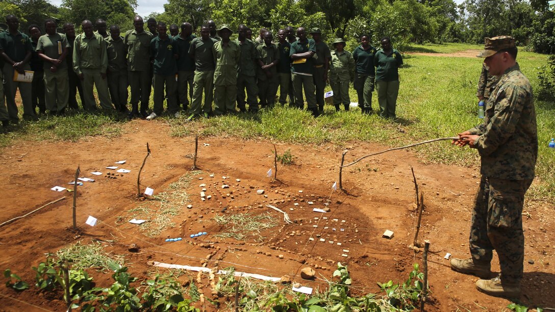 U.S. Marine Lance Cpl. Kyle McAuliffe, a rifleman assigned to the Theater Security Cooperation team with Special-Purpose Marine Air-Ground Task Force Crisis Response-Africa, shows Tanzanian park rangers different areas on a terrain model at the Selous Game Reserve in Matambwe, Tanzania, March 9, 2015. McAuliffe was one of approximately 15 Marines and Sailors from SPMAGTF-CR-AF to help teach the park rangers operation-order writing and land navigation skills.