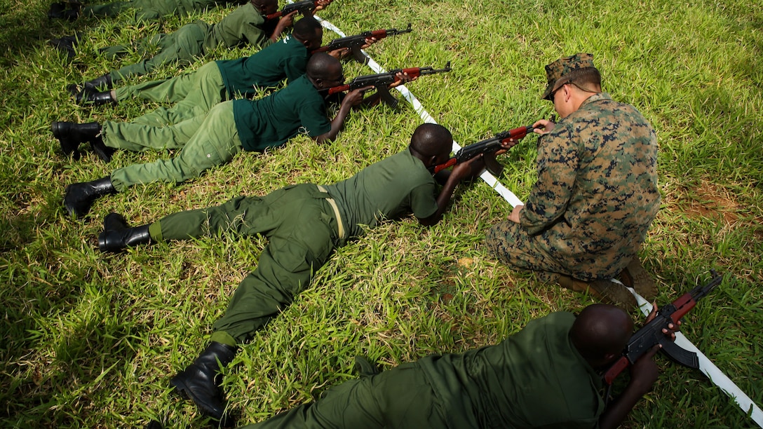 U.S. Marine Sgt. Kyle Kimbriel, right, the noncommissioned officer in charge of the Theater Security Cooperation team with Special-Purpose Marine Air-Ground Task Force Crisis Response-Africa, helps a Tanzanian park ranger aim an AKM assault rifle in the prone position during a combat marksmanship class at the Selous Game Reserve in Matambwe, Tanzania, March 3, 2015. The Marines and Sailors will spend the next several weeks teaching the Tanzanian park rangers infantry skills such as patrolling, offensive tactics, land navigation and mounted operations to aid in countering illicit trafficking.