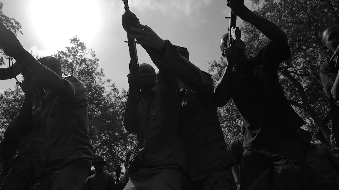 A U.S. Marine assigned to Special-Purpose Marine Air-Ground Task Force Crisis Response-Africa helps a Tanzanian park ranger aim an AKM assault rifle during a combat marksmanship class at the Selous Game Reserve in Matambwe, Tanzania, March 3, 2015. The Marines and Sailors will spend the next several weeks teaching the Tanzanian park rangers infantry skills such as patrolling, offensive tactics, land navigation and mounted operations to aid in countering illicit trafficking.