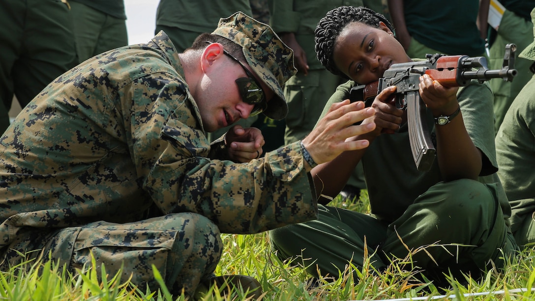 U.S. Marine Cpl. Joseph Kakascik, left, a rifleman and team leader assigned to the Theater Security Cooperation team with Special-Purpose Marine Air-Ground Task Force Crisis Response-Africa, shows a Tanzanian park ranger how to aim an AKM rifle from the sitting position at the Selous Game Reserve in Matambwe, Tanzania, March 3, 2015. The Marines and Sailors with the team will spend the next several weeks teaching the Tanzanian park rangers infantry skills such as patrolling, offensive tactics, land navigation and mounted operations to aid in counter illicit-trafficking efforts. 