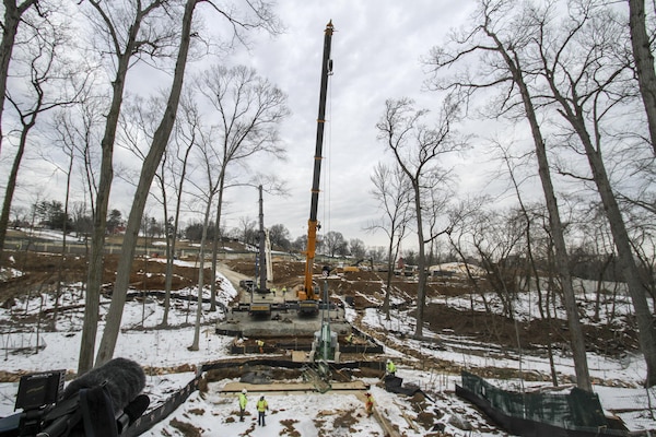 ARLINGTON , Va. -- Cranes stand by for the arrival of the first precast concrete support arches to arrive at the Arlington National Cemetery Millennium Project here March 3, 2015. The archways will support the loop road bridge, which spans a restored stream at the cemetery’s 27-acre expansion project. The project will add nearly 30,000 burial and niche spaces with a mix of above-ground columbariums and in-ground burials. (U.S. Army photo/Patrick Bloodgood)