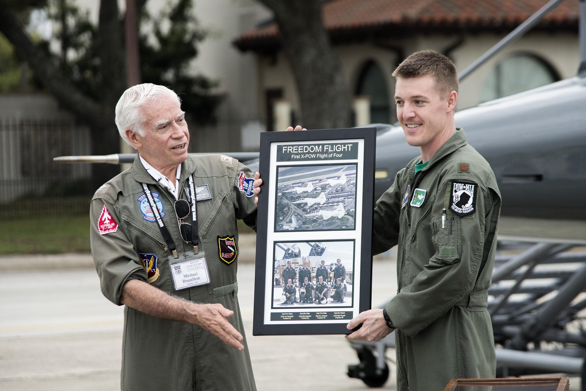 Retired Air Force Col. Mike Brazelton, former Vietnam War POW, and Maj. Joe Elam, 560th Flying Training Squadron evaluator pilot, display the Freedom Flight photo of the first POW Flight of Four during the 560th Flying Training Squadron Artifact Dedication ceremony and open house March 20 at Joint Base San Antonio-Randolph. The annual event, in conjunction with the 42nd Freedom Flyer Reunion and 18th Annual POW/MIA Symposium, honors all POWs held captive during the Vietnam War. The tradition began when members of the 560th Flying Training Squadron were given the task to retrain more than 150 POWs returning to flying status. Brazelton’s aircraft was shot down during a mission over North Vietnam Aug. 7, 1966, and was held captive by the North Vietnamese until his release March 4, 1973. (U.S. Air Force Photo by Johnny Saldivar)