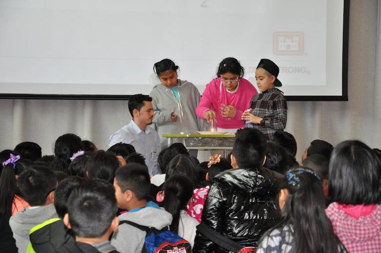 Erwin Galloza, mechanical engineer, U.S. Army Corps of Engineers, New York District performs a science experiment with three student volunteers. 