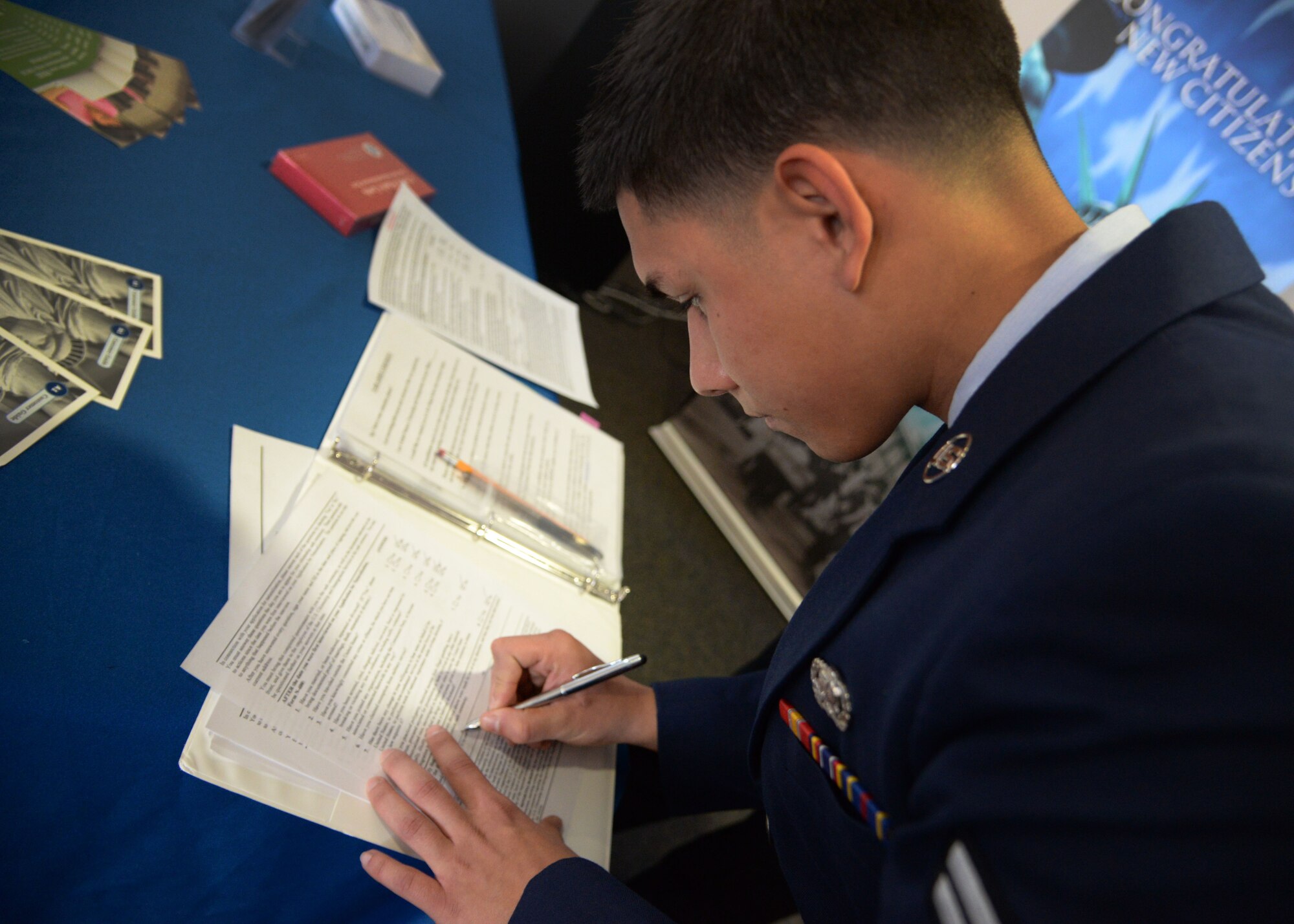 U.S. Air Force Airman 1st Class Dominik Green, 27th Special Operations Logistics Readiness Squadron storage and issue specialist, signs official documents prior to a naturalization ceremony March 20, 2015 at Cannon Air Force Base, N.M. Green was born in Mannheim, Germany and was one of four presented with their citizenship by officials from the United States Citizenship and Immigration Services field office in Albuquerque, New Mexico. (U.S. Air Force photo/Staff Sgt. Alex Mercer) 