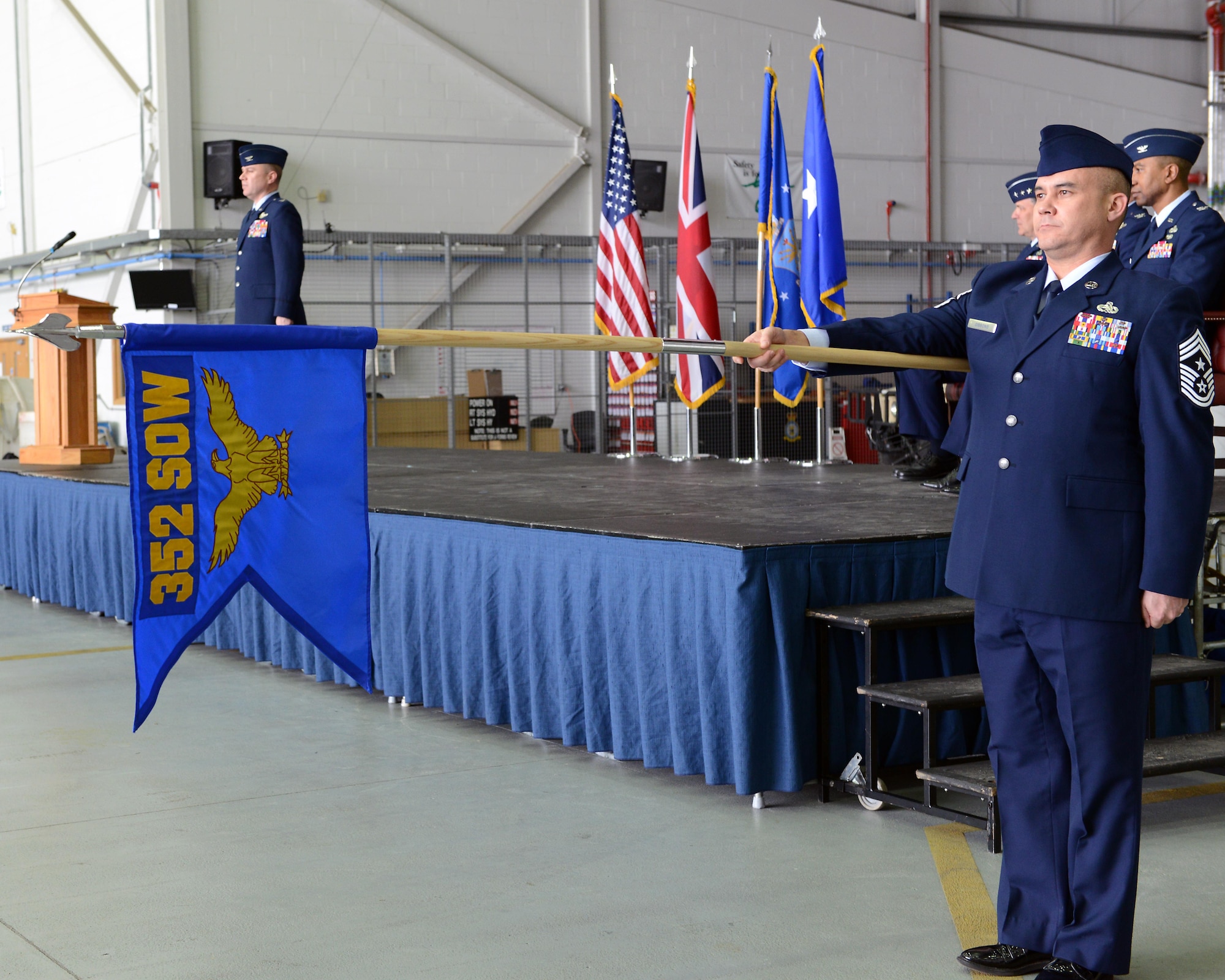 U.S. Air Force Chief Master Sgt. Robert Gibbons II presents the 352nd Special Operations Wing guideon during the 352nd SOW redesignation ceremony March 23, 2015, held in Hangar 814 on RAF Mildenhall, England. During the ceremony, the 752nd Special Operations Group and the (U.S Air Force photo by Tech. Sgt. Stacia Zachary/Released)