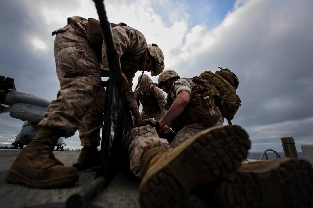 U.S. Marines with Combat Logistics Battalion 15, 15th Marine Expeditionary Unit, lift a simulated casualty onto a stretcher during a mass casualty drill as part of Composite Training Unit Exercise (COMPTUEX) aboard the USS Essex (LDH 2) off the coast of San Diego March 22, 2014. CLB-15 is the MEU’s logistics combat element and provides both routine and emergency combat medical care for the more than 2,200 Marines. (U.S. Marine Corps photo by Cpl. Elize McKelvey/Released)