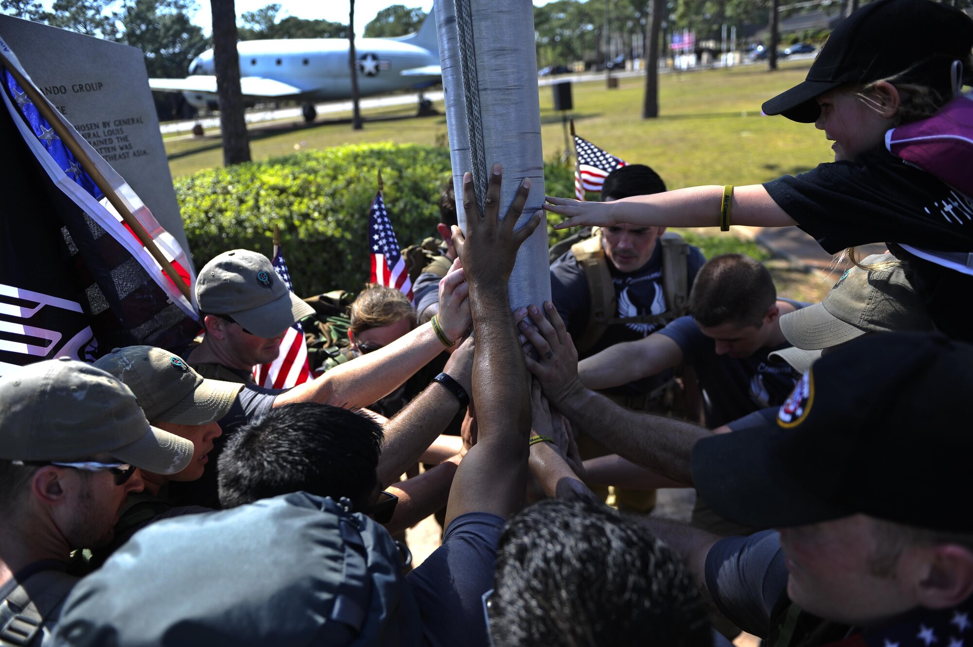 Airmen from the 1st Special Operations Wing place their hands on a flag pole to complete a 450-mile ruck march from MacDill Air Force Base, Fla., to Hurlburt Field, Fla., March 20, 2015. The 11 Air Commandos carried flags with the names of the seven fallen Special Operations Command Marines and four Army National Guard air crew members that lost their lives during a training mission, March 10, 2015. (U.S. Air Force photo/Senior Airman Christopher Callaway/Released)