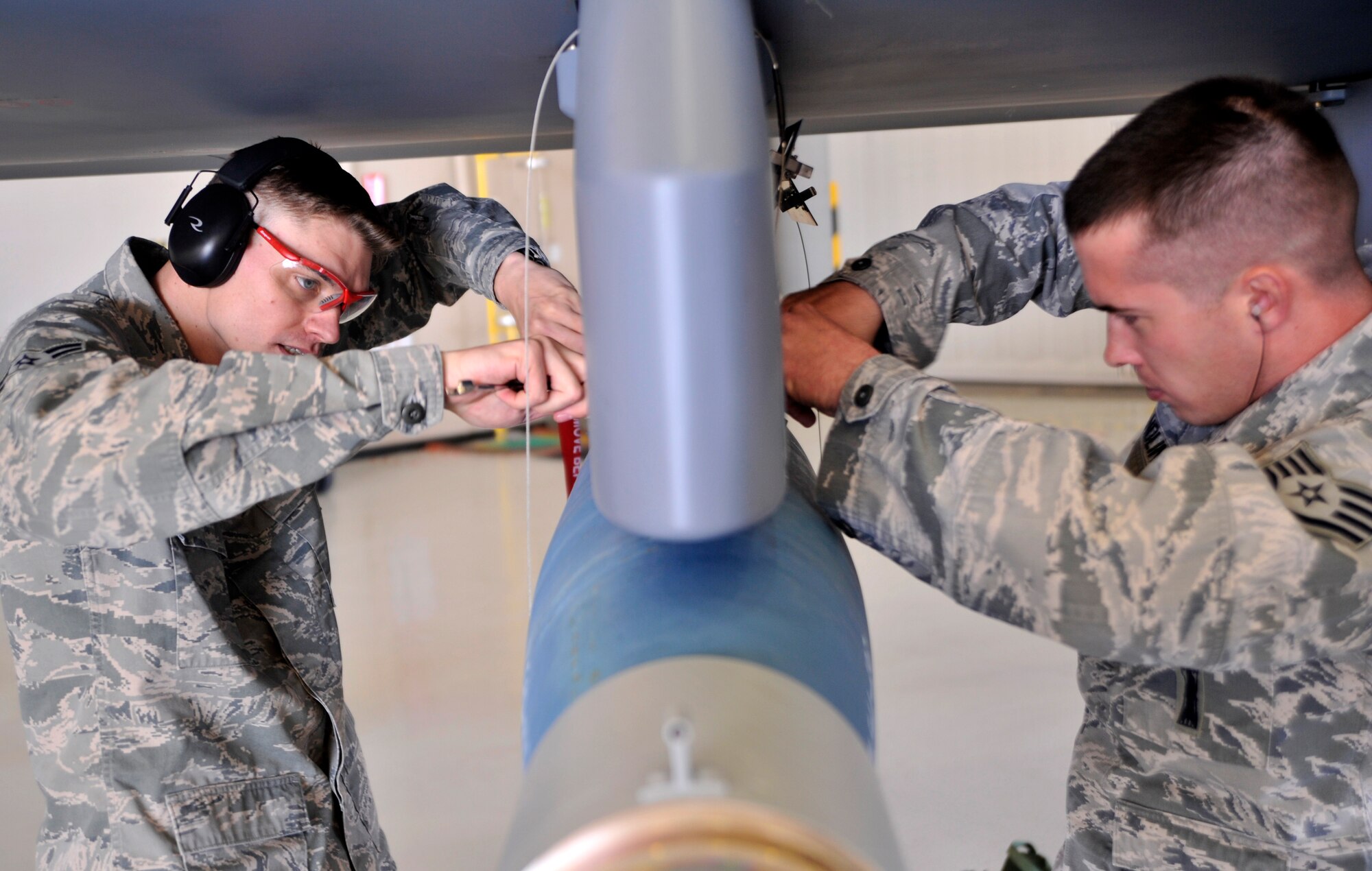Airman 1st Class Kenneth Rogers, 432nd Aircraft Maintenance Squadron weapons load crew member, left, and Staff Sgt. Jason Sandlin, 432nd AMXS weapons team chief, finish installing an inert GBU-12 Paveway II laser guided bomb on an MQ-9 Reaper during the 432nd Maintenance Group Load Crew of the Year competition Feb. 13, 2015, at Creech Air Force Base, Nevada. The Load Crew of the Year competition challenges three-man weapons loading teams from each aircraft maintenance unit against each other as a friendly competition to further skills and promote camaraderie and can trace their roots since before the Korean War. (U.S. Air Force photo by Airman 1st Class Christian Clausen/Released)