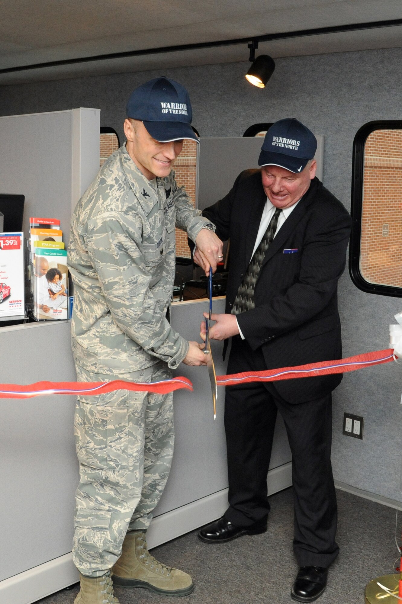 Col. Robert Cook, 319th Air Base Wing vice commander, and Larry Stuker, Service Credit Union contact center assistant vice president, cut the ribbon to open a new SCU branch on Grand Forks Air Force Base, N.D., March 23, 2015. The branch is currently in a temporary facility near the base exchange and will move into a permanent building in June. (U.S. Air Force photo by Staff Sgt. David Dobrydney/Released)