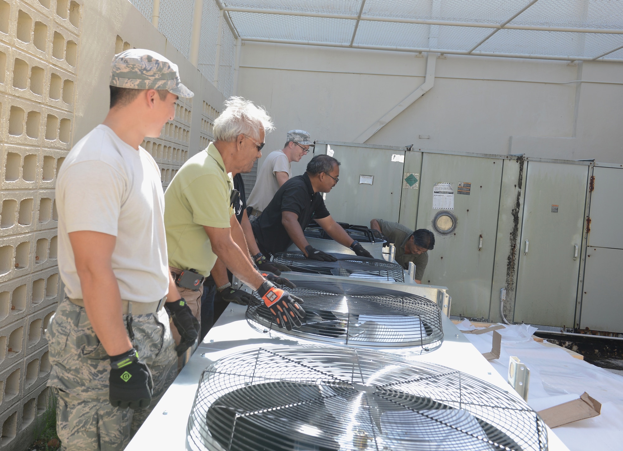 36th Civil Engineer Squadron heating, ventilation and air conditioning technicians work together to move a condensing unit for installation March 12, 2015, at Andersen Air Force Base, Guam. The mission of the HVAC Flight is to install, maintain, and repair different systems on base. (U.S. Air Force photo by Airman 1st Class Arielle Vasquez/Released)