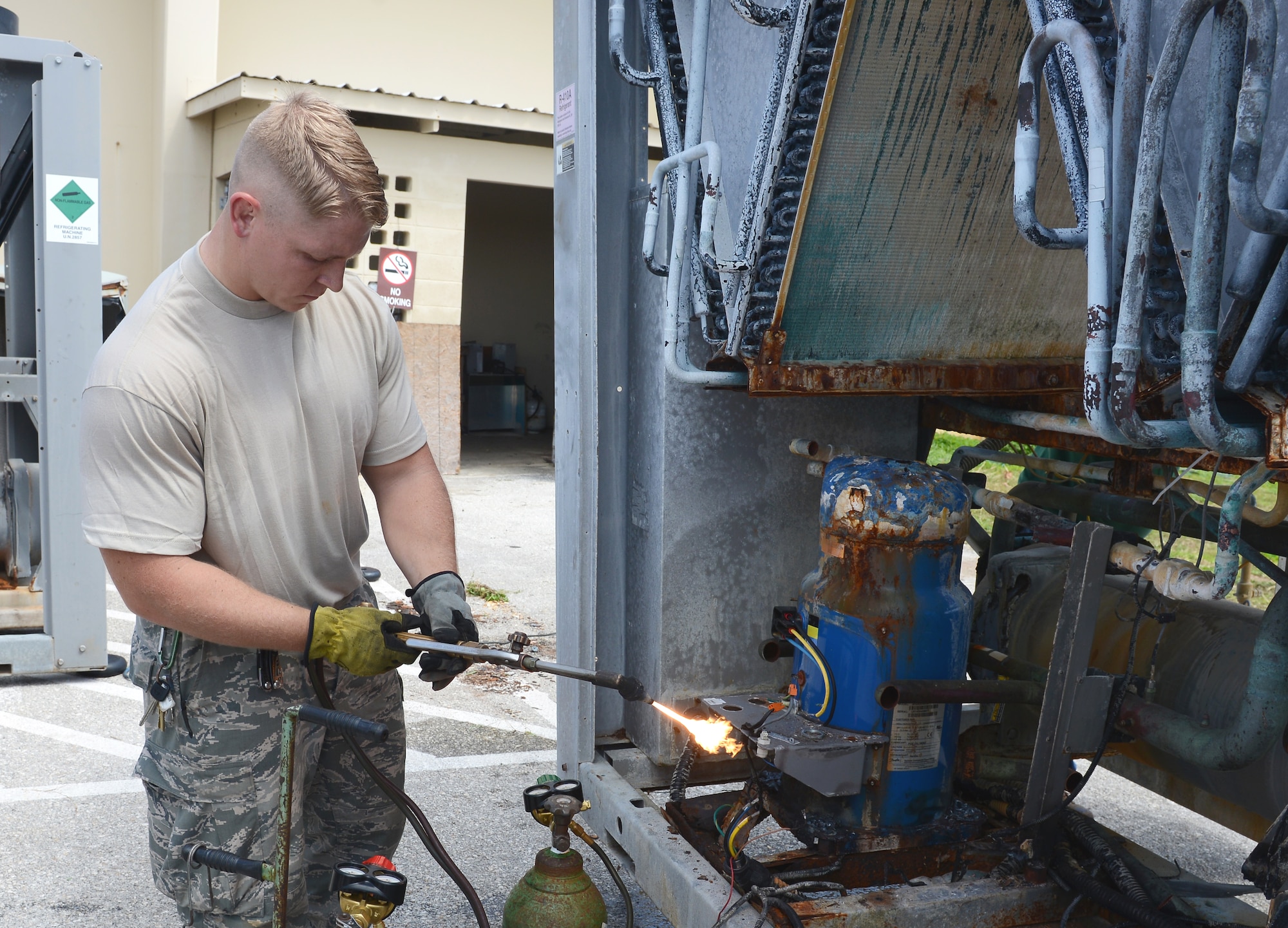 Staff Sgt. Ricky Kranning, 36th Civil Engineer Squadron heating, ventilation and air conditioning technician, uses a cutting torch to cut compressors out of a unit March 11, 2015, at Andersen Air Force Base, Guam. The mission of the HVAC Flight is to install, maintain, and repair different systems on base. (U.S. Air Force photo by Airman 1st Class Arielle Vasquez/Released)
