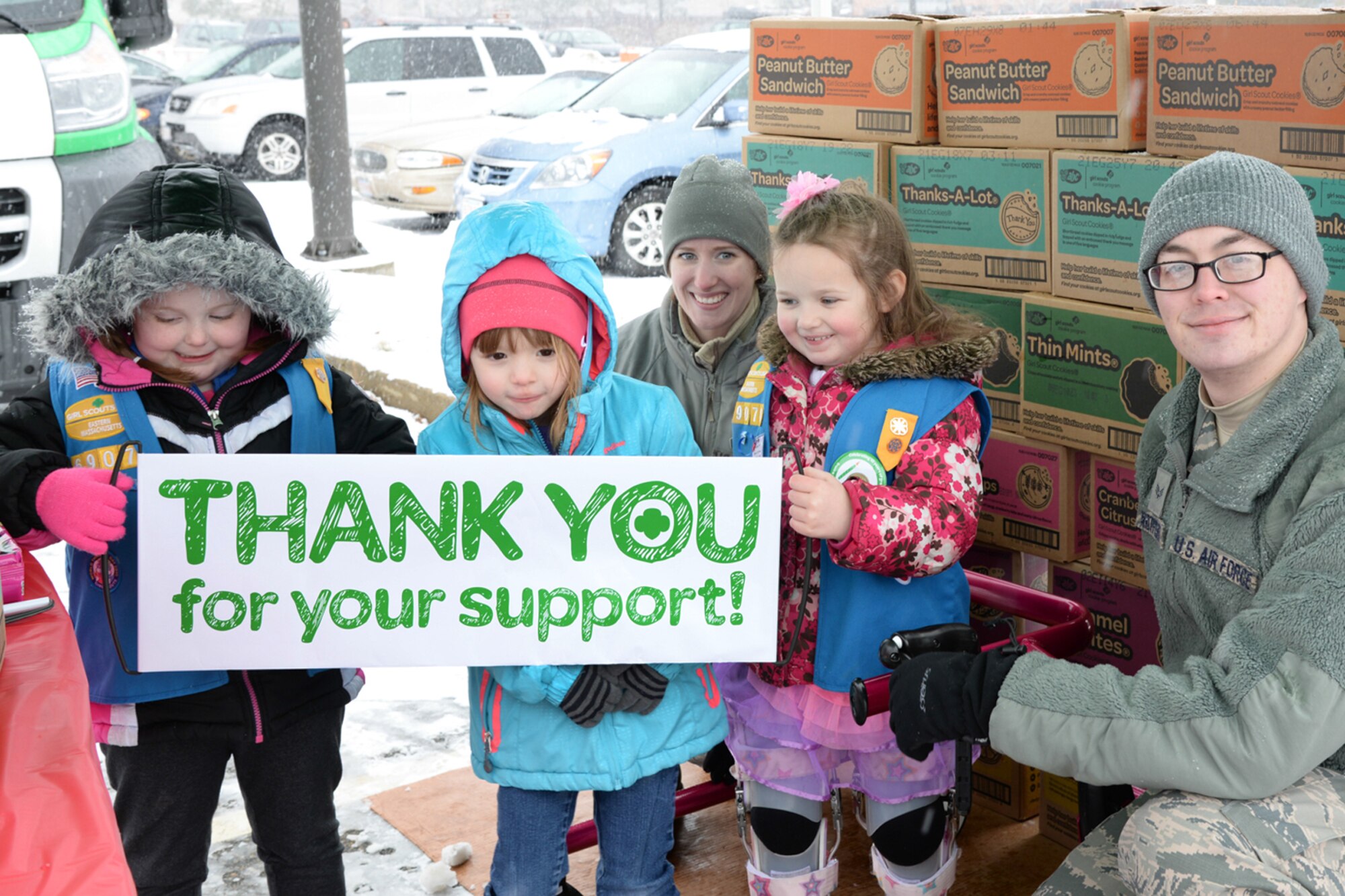 Airman 1st Class Samantha Keller and Senior Airman Nickolas Widtfeldt, both technicians with the 66th Medical Squadron, pause for a photo with Girl Scouts during Operation Cookie Drop at Hanscom Air Force Base, Mass., March 21, 2015. The event provides an opportunity for the Girl Scouts to deliver cookie donations in person to some of the military members and veterans their Cookies for a Cause program supports. (U.S. Air Force photo by Linda LaBonte Britt) 
