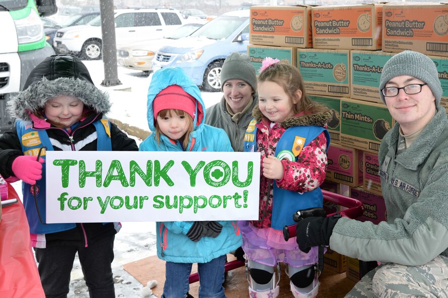 Airman 1st Class Samantha Keller and Senior Airman Nickolas Widtfeldt, both technicians with the 66th Medical Squadron, pause for a photo with Girl Scouts during Operation Cookie Drop at Hanscom Air Force Base, Mass., March 21, 2015. The event provides an opportunity for the Girl Scouts to deliver cookie donations in person to some of the military members and veterans their Cookies for a Cause program supports. (U.S. Air Force photo by Linda LaBonte Britt) 
