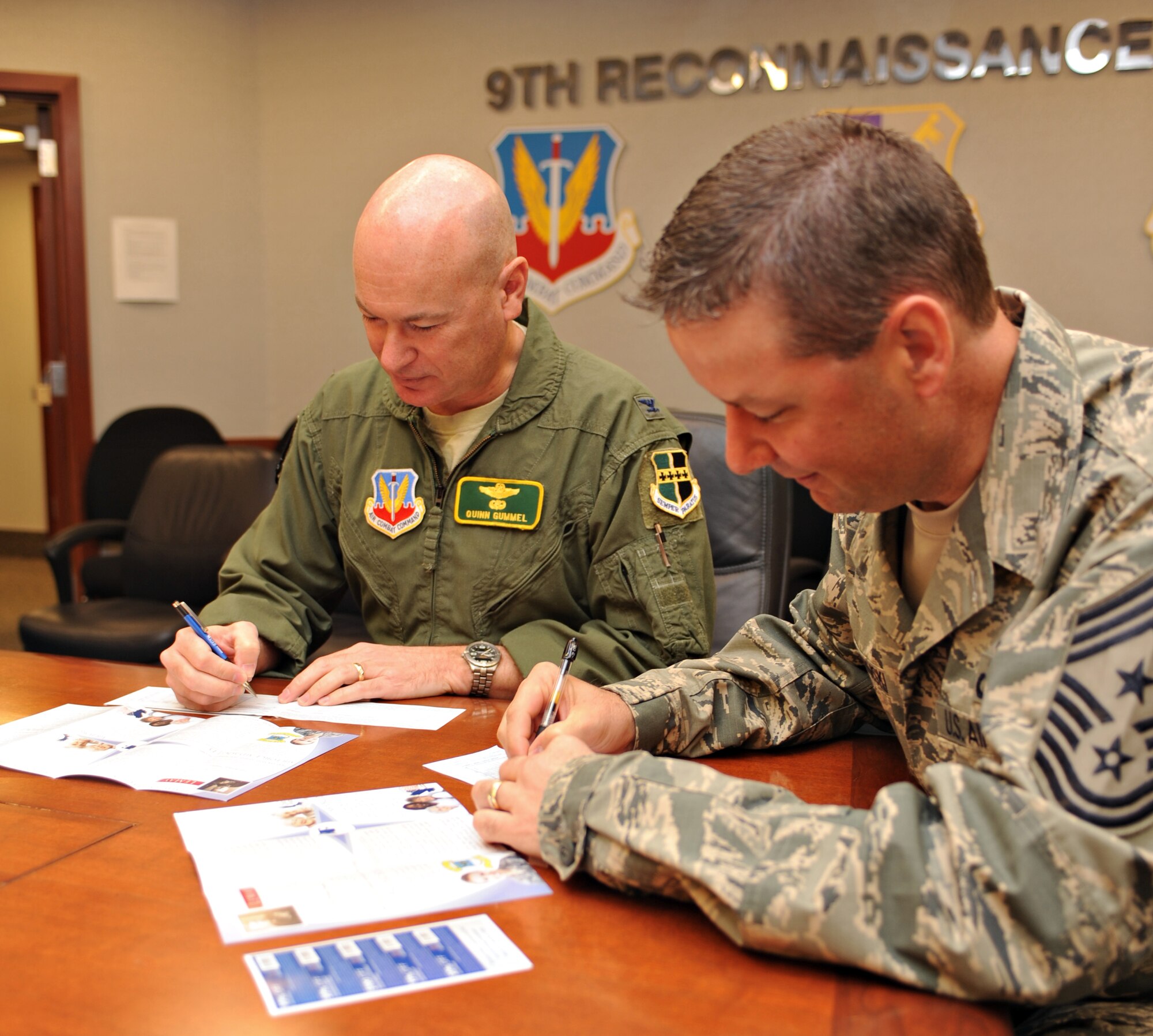 Col. Quinn Gummel (left), 9th Reconnaissance Wing vice commander, and Chief Master Sgt. Randy  Kwiatkowski, 9th RW command chief, make their contributions to the Air Force Assistance Fund March 23, 2015, at Beale Air Force Base, Calif. The campaign is an Air Force-wide program that benefits active-duty members, reserve, guard, retirees, and surviving spouses and families. (U.S. Air Force photo by Robert Scott/Released) 