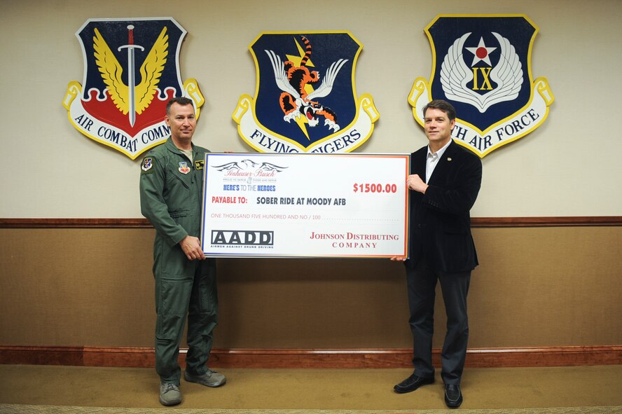 Tim Keller, Johnson Distributing Company consumer awareness and education, presents a check to U.S. Air Force Col. Chad Franks, 23d Wing commander, for the Airman Against Drunk Driving (AADD) program March 23, 2015 at Moody Air Force Base, Ga. Previously known as ‘Sober Ride,’ AADD is a volunteer program that is designed to help Airmen return home safely after a night out. The donation will fund future AADD events. (U.S. Air Force photo by Senior Airman Olivia Bumpers/Released)