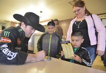 Laura Gurule and her two sons, Jordan, 8, and Noah, 4, get an autograph from professional bull rider LJ Jenkins.  The PBR brought Jenkins and the two bulls to Kirtland during a tour stop in Albuquerque March 19. More than a hundred Team Kirtland members stopped by to greet Jenkins and take pictures with the animals. (Photo by Todd Berenger)