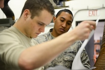 Staff Sgt. Kamuela Kalilikane, 91st Missile Operations Squadron facilities maintenance team training instructor, goes through technical orders with Airman 1st Class Jacob O’Leary, 91st MOS FMT, during training on Minot Air Force Base, N.D., March 3, 2015. To become a FMT instructor, one must be 100 percent certified on trainable tasks and attend the 20th Air Force Intercontinental Ballistic Missile Maintenance Instructional Course. (U.S. Air Force photo/Senior Airman Brittany Y. Bateman)