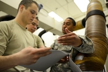 Staff Sgt. Kamuela Kalilikane, 91st Missile Operations Squadron facilities maintenance team training instructor, goes through technical orders with his students during training on Minot Air Force Base, N.D., March 3, 2015. FMT instructors provide instruction to produce competent facilities maintenance technicians that are able to perform periodic maintenance, troubleshoot, and repair diesel-electrical units and environmental control systems that sustain unmanned launch facilities. (U.S. Air Force photo/Senior Airman Brittany Y. Bateman)