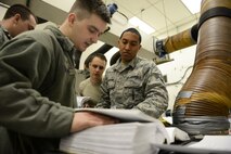 Staff Sgt. Kamuela Kalilikane, 91st Missile Operations Squadron facilities maintenance team training instructor, goes through technical orders with his students during training on Minot Air Force Base, N.D., March 3, 2015. FMT instructors provide instruction to produce competent facilities maintenance technicians that are able to perform periodic maintenance, troubleshoot, and repair diesel-electrical units and environmental control systems that sustain unmanned launch facilities. (U.S. Air Force photo/Senior Airman Brittany Y. Bateman)
