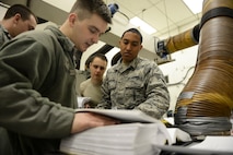 Staff Sgt. Kamuela Kalilikane, 91st Missile Operations Squadron facilities maintenance team training instructor, goes through technical orders with his students during training on Minot Air Force Base, N.D., March 3, 2015. FMT instructors provide instruction to produce competent facilities maintenance technicians that are able to perform periodic maintenance, troubleshoot, and repair diesel-electrical units and environmental control systems that sustain unmanned launch facilities. (U.S. Air Force photo/Senior Airman Brittany Y. Bateman)