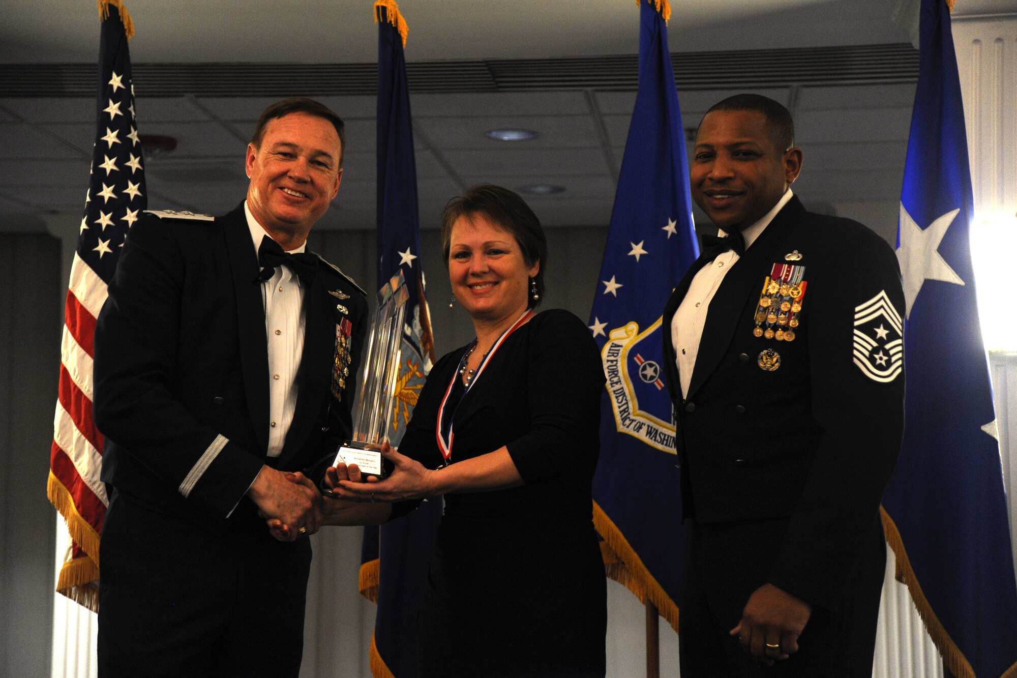 Annette Bonaro, Air Force District of Washington, accepts the 2014 AFDW Annual Awards Civilian Volunteer of the Year trophy from AFDW Commander Maj. Gen. Darryl Burke and AFDW Command Chief Master Sgt. Farrell Thomas during the awards ceremony at Joint Base Anacostia-Bolling, D.C., March 20, 2015. (U.S. Air Force photo/Master Sgt. Tammie Moore)