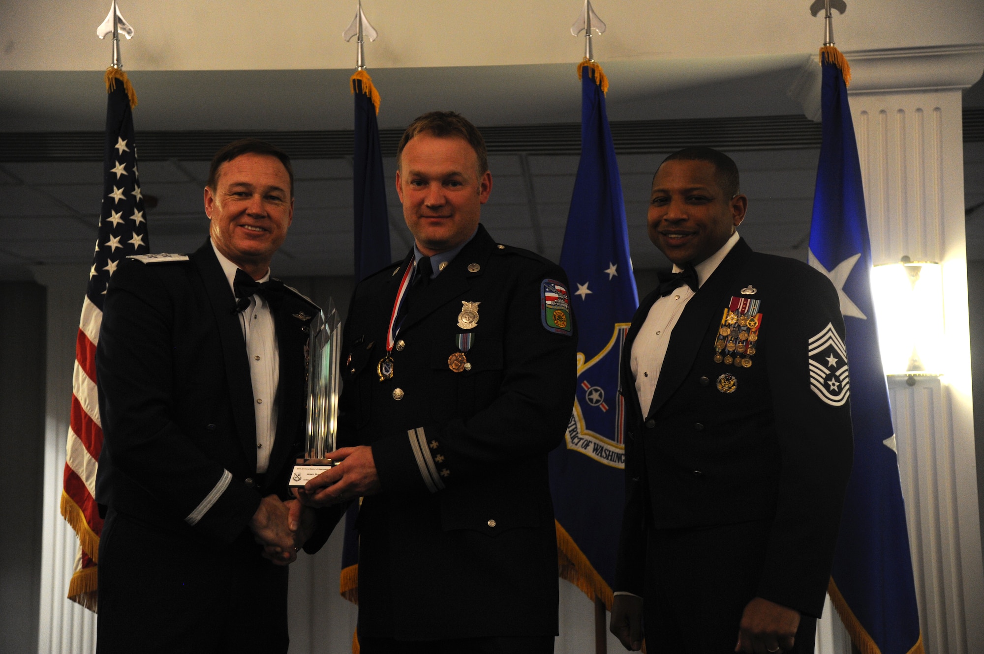 Adam Burak, Jr., 11th Wing, accepts the 2014 Air Force District of Washington Annual Awards Civilian Category II of the Year trophy from AFDW Commander Maj. Gen. Darryl Burke and AFDW Command Chief Master Sgt. Farrell Thomas during the awards ceremony at Joint Base Anacostia-Bolling, D.C., March 20, 2015. (U.S. Air Force photo/Master Sgt. Tammie Moore))