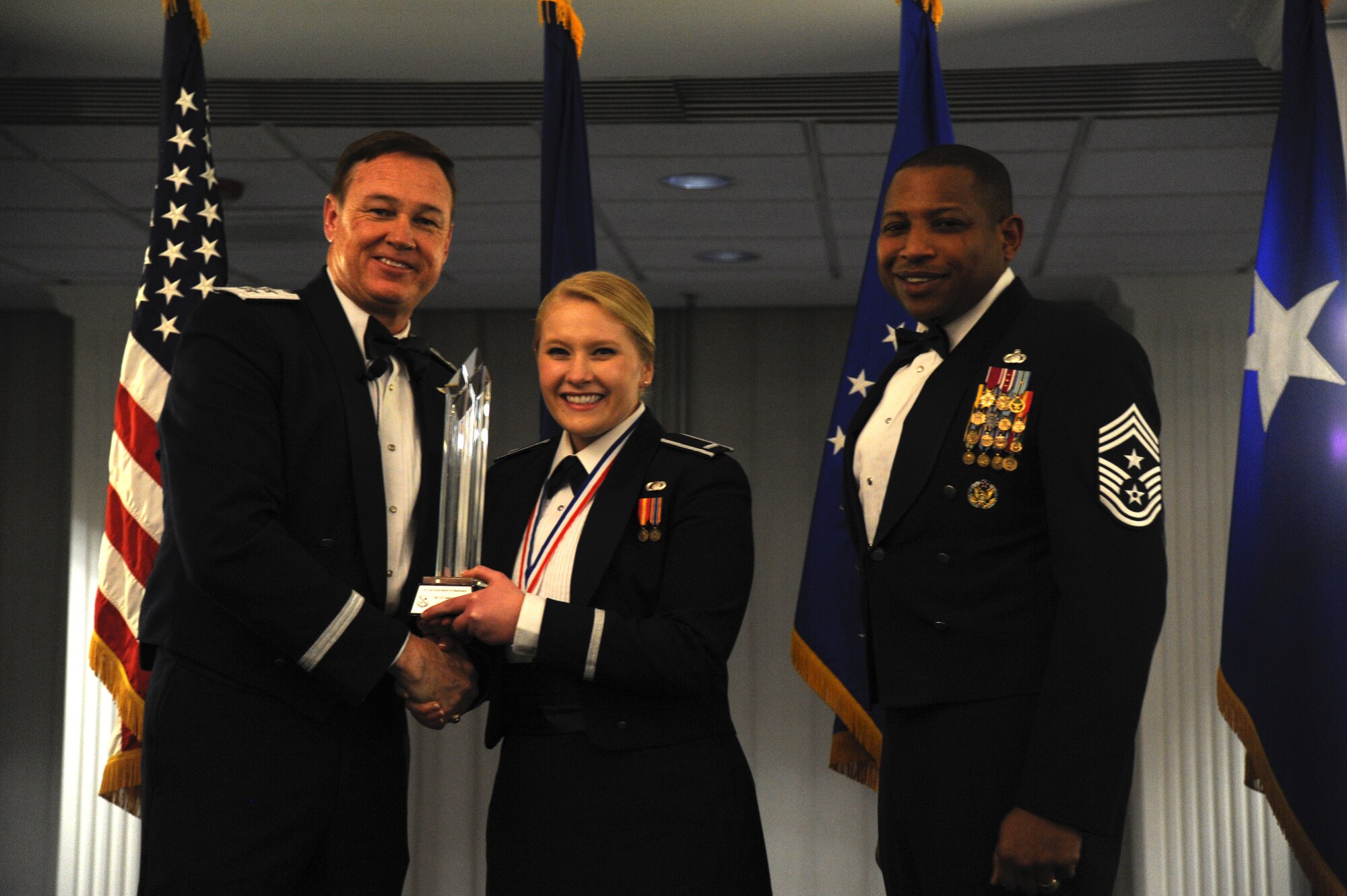 1st Lt. Alexandra Ellis, 11th Wing, accepts the 2014 Air Force District of Washington Annual Awards CGO of the Year trophy from AFDW Commander Maj. Gen. Darryl Burke and AFDW Command Chief Master Sgt. Farrell Thomas during the awards ceremony at Joint Base Anacostia-Bolling, D.C., March 20, 2015. (U.S. Air Force photo/Master Sgt. Tammie Moore)