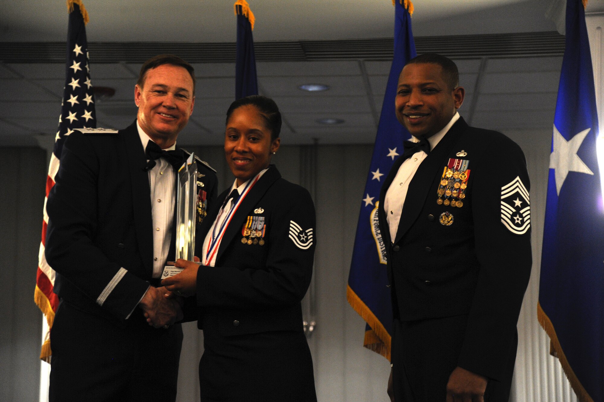 Tech. Sgt. Marshe Greene, 844th Communications Group, accepts the 2014 Air Force District of Washington Annual Awards Military Volunteer of the Year trophy from AFDW Commander Maj. Gen. Darryl Burke and AFDW Command Chief Master Sgt. Farrell Thomas during the awards ceremony at Joint Base Anacostia-Bolling, D.C., March 20, 2015. (U.S. Air Force photo/Master Sgt. Tammie Moore)
