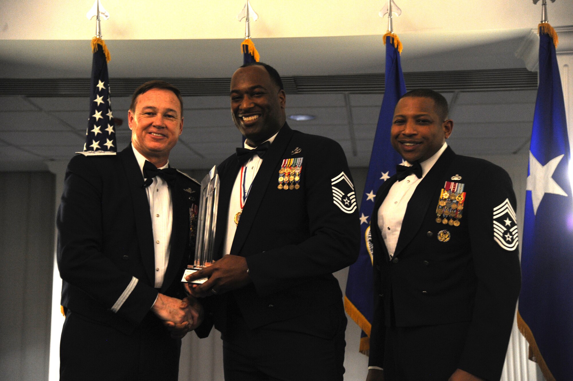 Senior Master Sgt. Dana Council, 11th Wing, accepts the 2014 Air Force District of Washington Annual Awards SNCO of the Year trophy from AFDW Commander Maj. Gen. Darryl Burke and AFDW Command Chief Master Sgt. Farrell Thomas during the awards ceremony at Joint Base Anacostia-Bolling, D.C., March 20, 2015. (U.S. Air Force photo/Master Sgt. Tammie Moore)