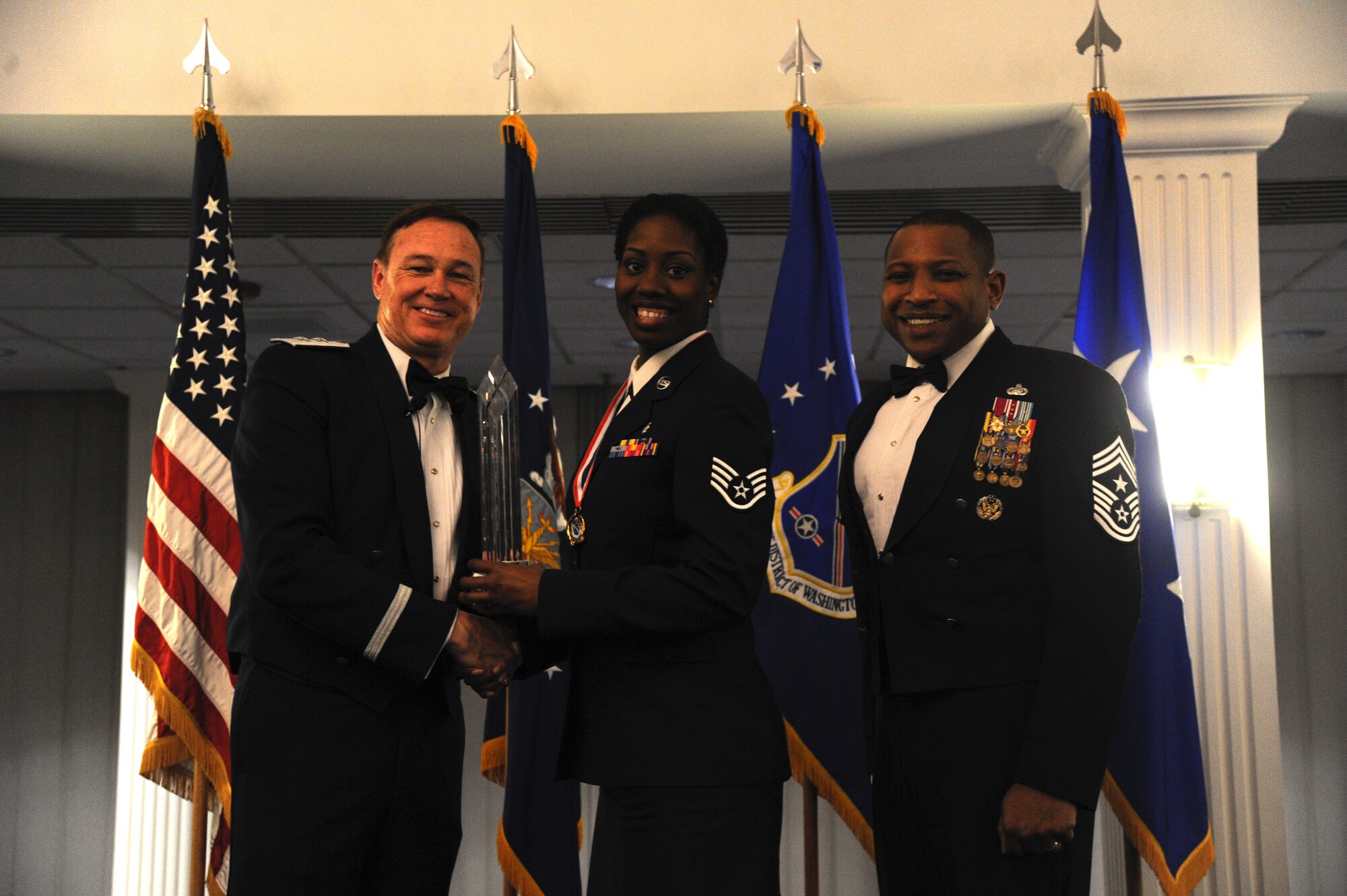Staff Sgt. Sherella Walker, 79th Medical Wing, accepts the 2014 Air Force District of Washington Annual Awards NCO of the Year trophy from AFDW Commander Maj. Gen. Darryl Burke and AFDW Command Chief Master Sgt. Farrell Thomas during the awards ceremony at Joint Base Anacostia-Bolling, D.C., March 20, 2015. (U.S. Air Force photo/Master Sgt. Tammie Moore)