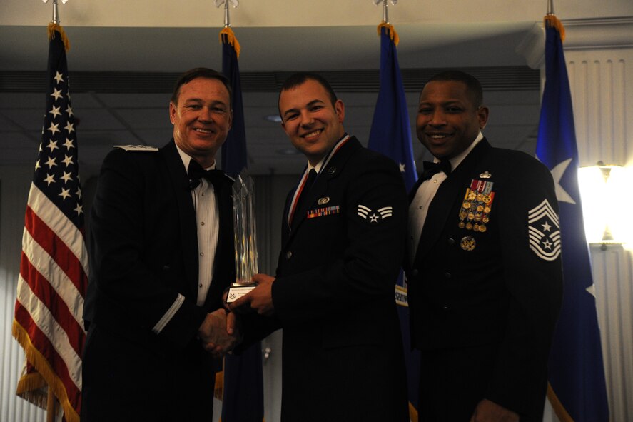 Senior Airman Logan Reynolds, 844th Communications Group, accepts the 2014 Air Force District of Washington Annual Awards Airman of the Year trophy from AFDW Commander Maj. Gen. Darryl Burke and AFDW Command Chief Master Sgt. Farrell Thomas during the awards ceremony at Joint Base Anacostia-Bolling, D.C., March 20, 2015. (U.S. Air Force photo/Master Sgt. Tammie Moore)