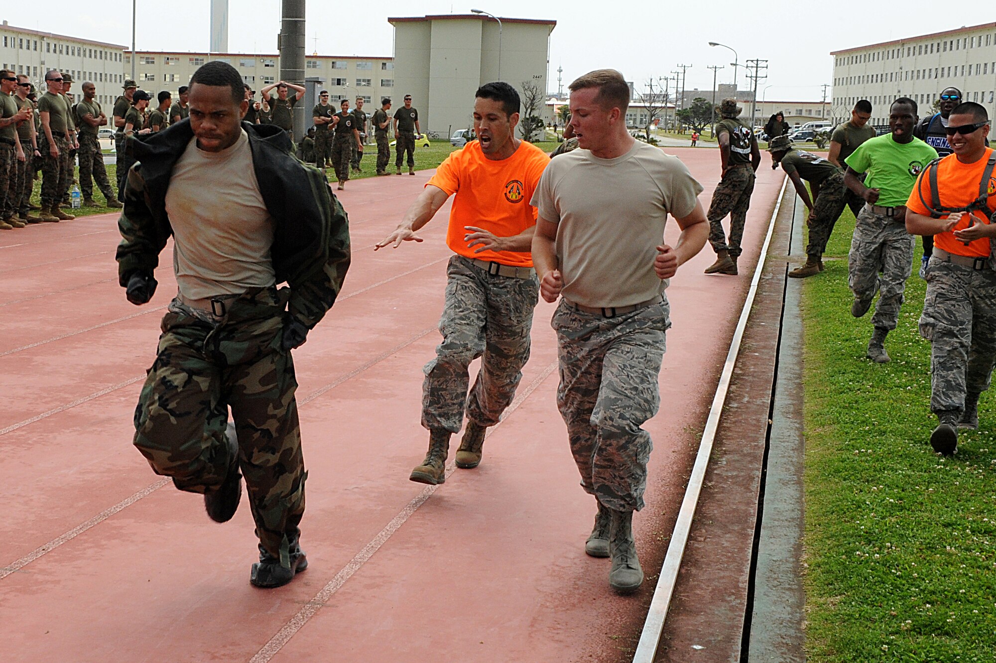 U.S. Air Force members of the 18th Civil Engineer Group encourage their teammate to the finish during a relay race on Camp Hansen, Japan, March 20, 2015. The relay consisted of four laps around a 400-meter track. Runners had to add a layer of chemical protective equipment during each lap. More than 500 Airmen, Marines and Sailors participated in this year’s annual competition. (U.S. Air Force photo by Airman 1st Class Stephen G. Eigel))
