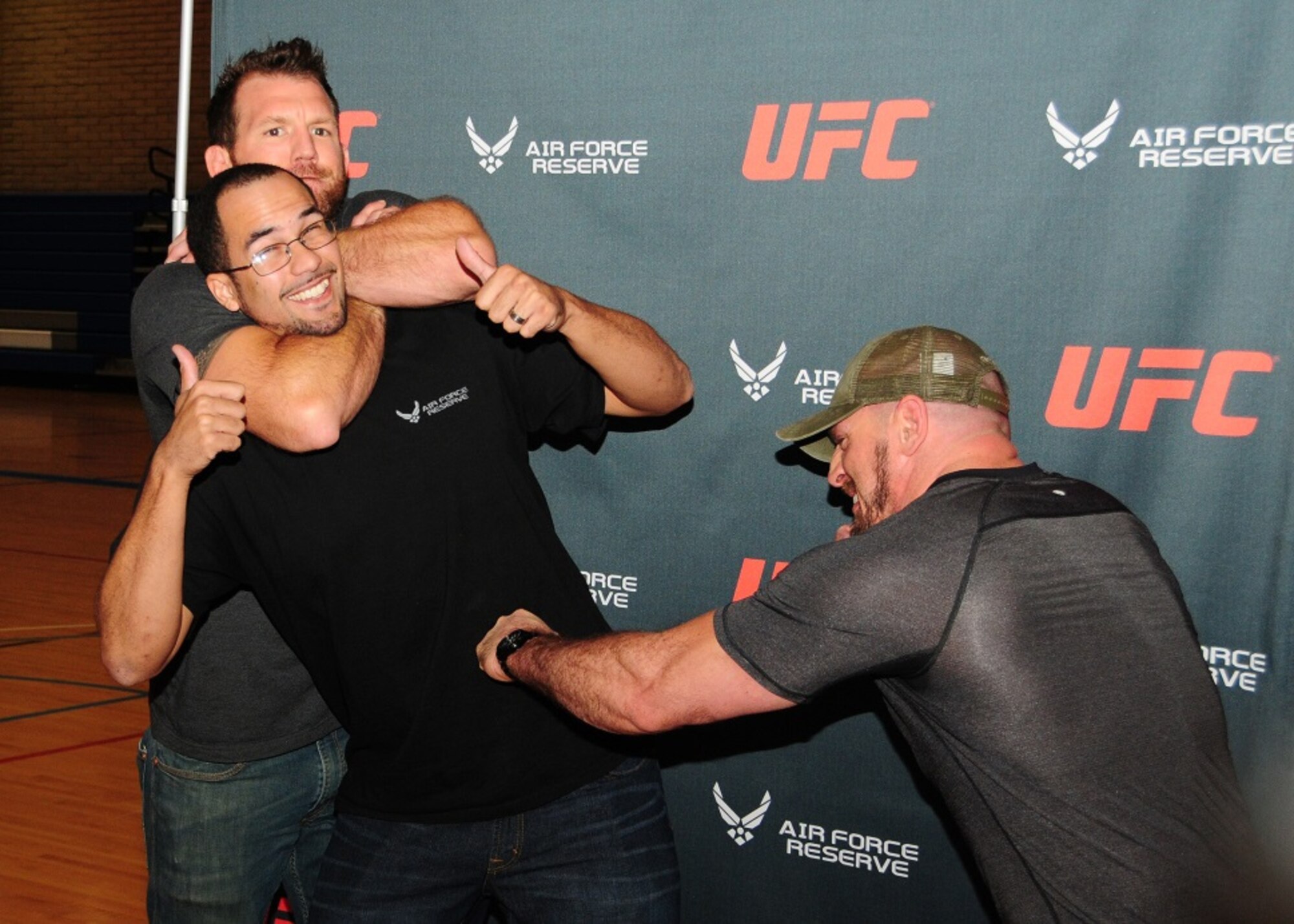 Mr. Jerrus Wagstaff, spouse, is put in a choke hold by Ryan “Darth” Bader, Ultimate Fighting Champion fighter and Mike Dolce, UFC fit coach, pretends to punch Mar 21 during the UFC Fitness Tour 2015 at the Bryant Fitness Center, Luke Air Force Base, Ariz. (U.S. Air Force photo taken by Tech. Sgt. Louis Vega Jr.)
