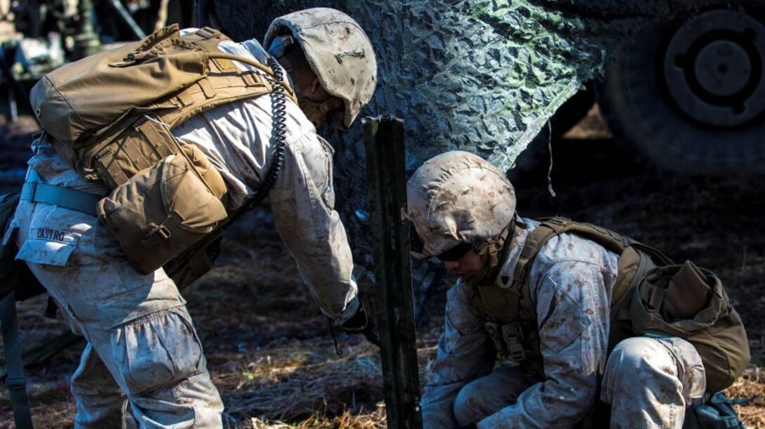Marines with Fox Battery, 2nd Battalion, 10th Marine Regiment, 2nd Marine Division set the foundation for the camouflage netting over a howitzer and tactical vehicles during Exercise Rolling Thunder aboard Fort Bragg, N.C., March 7, 2015. Establishing this camouflage covering enables Marines to train while concealing themselves in their surroundings. 