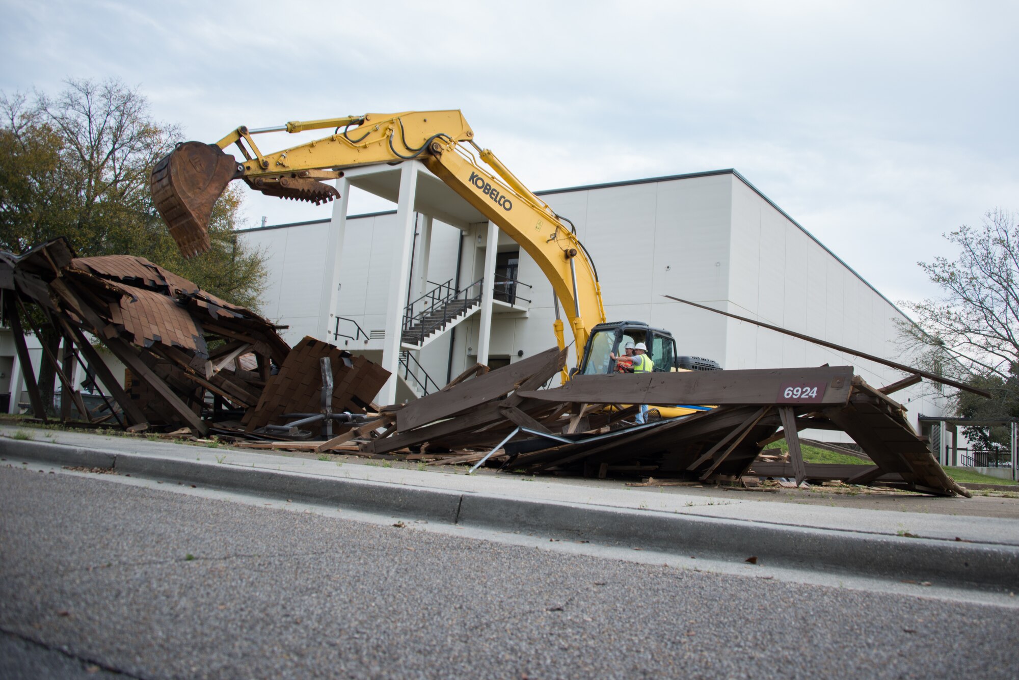 Col. Susan Airola-Skully, 81st Mission Support Group commander, and Jamie Bean, base operations support contractor, operate an excavator to begin the demolition of Hewes Hall, March 18, 2015, at Keesler Air Force Base, Miss. The prime demolition contractor is Bean Excavating.  (U.S. Air Force photo by Marie Floyd)