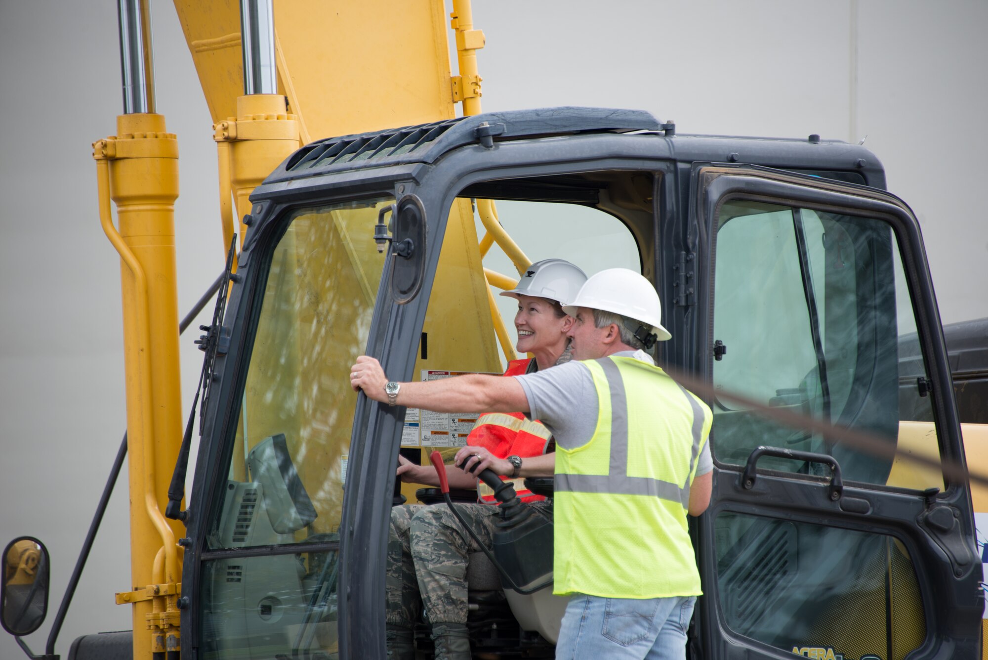 Col. Susan Airola-Skully, 81st Mission Support Group commander, and Jamie Bean, base operations support contractor, operate an excavator to begin the demolition of Hewes Hall, March 18, 2015, at Keesler Air Force Base, Miss. The prime demolition contractor is Bean Excavating.  (U.S. Air Force photo by Marie Floyd)