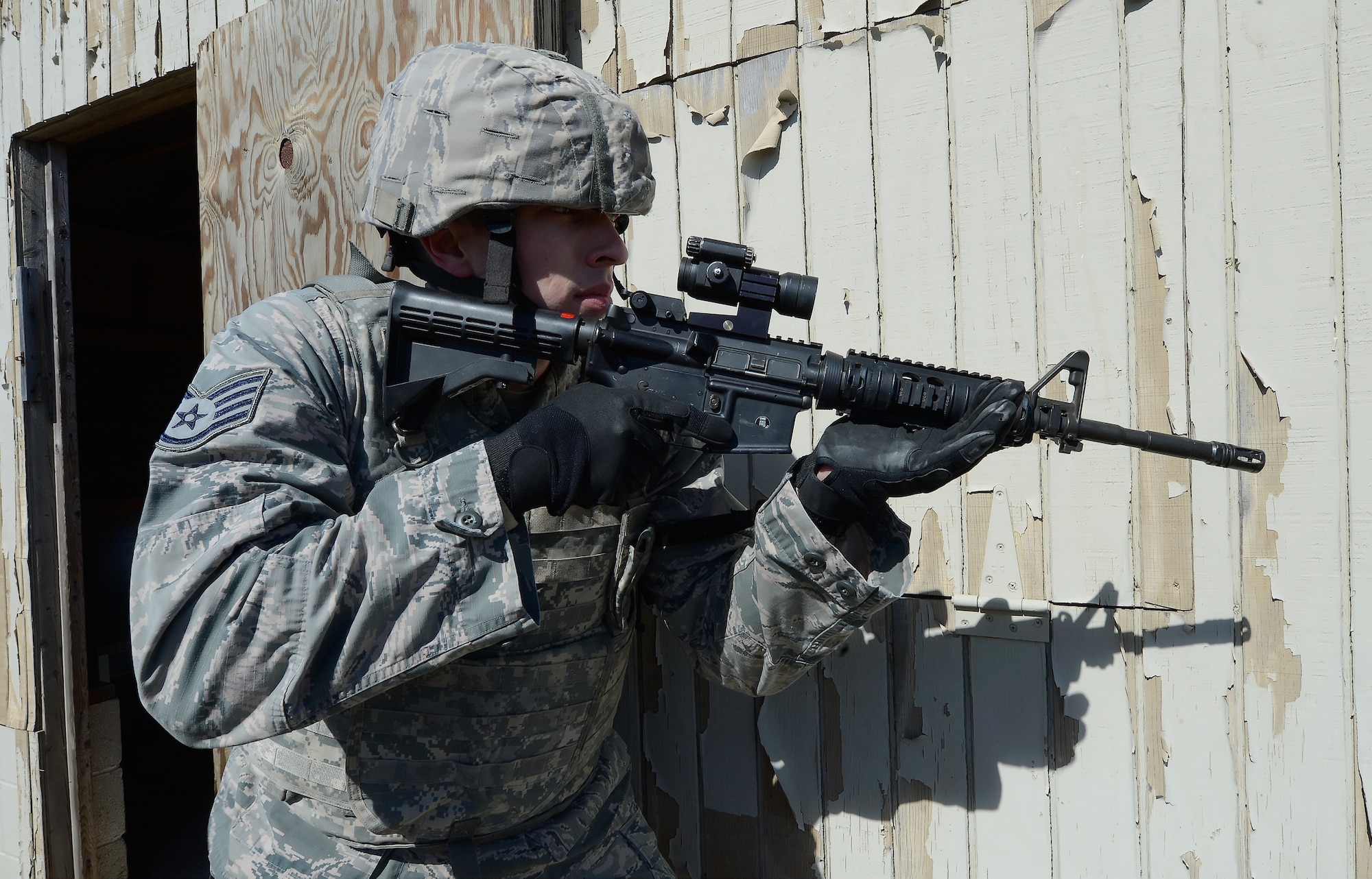 Staff Sgt. Brian Lecates, 436th Security Forces Squadron breech team member, takes-up a protective stance along the wall of a building after the building was  entered by his team during a training exercise March 18, 2015, on Dover Air Force Base, Del. Lecates carries an M-4 carbine, a weapon tailored for use in close-quarters due to the collapsible stock and shortened barrel. The 2015 Dover Air Force Base Honorary Commanders took part in a tour of the 436th Mission Support Group to better understand the Group's mission and capabilities. (U.S. Air Force photo/Greg L. Davis)