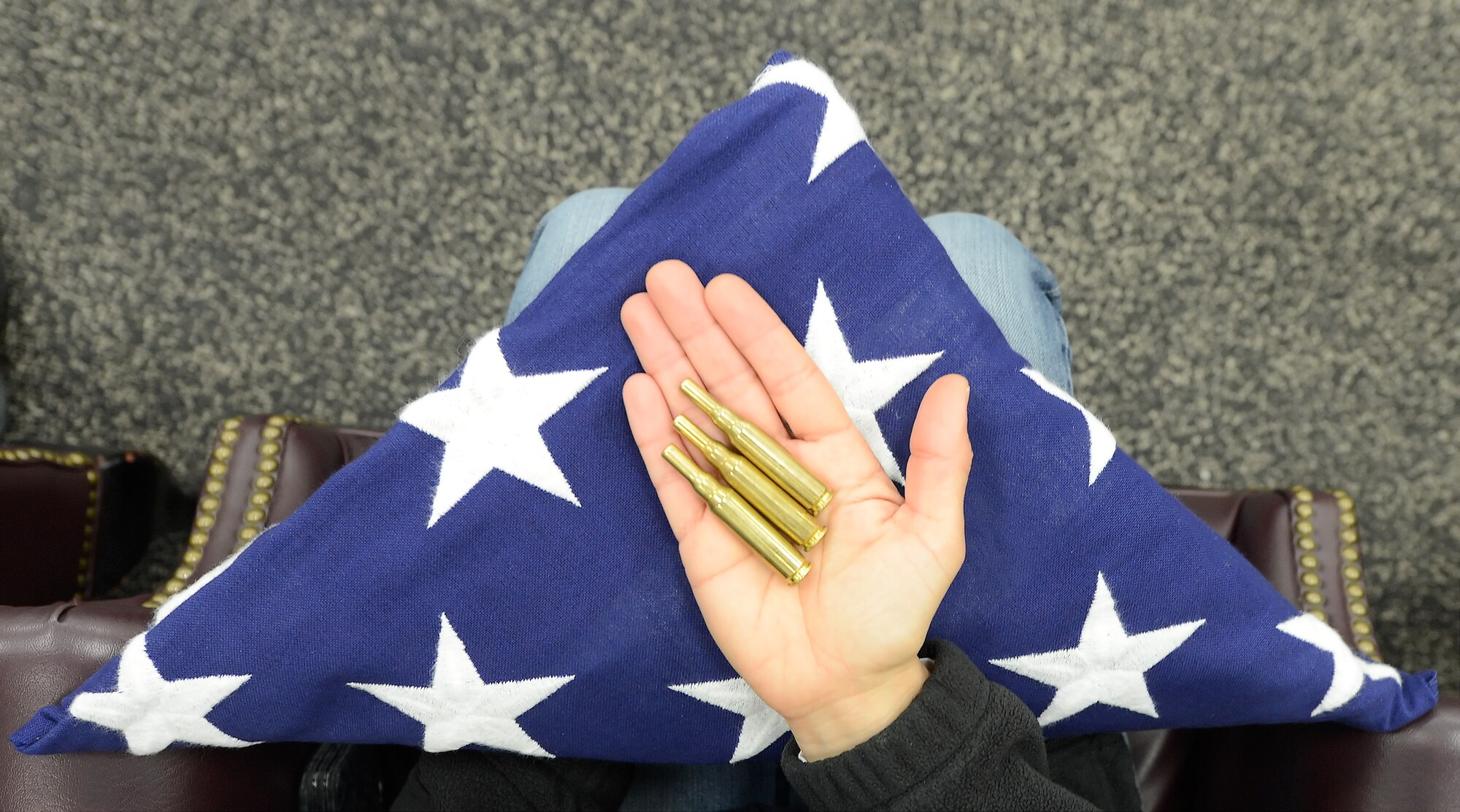 Elements representative of those given to families of fallen service members and veterans in the form of a folded flag and shell casings rest in the opened hand of Lori Ewald,  436th Force Support Squadron honorary commander, after being presented to her following a training demonstration by the 436th Mission Support Group Base Honor Guard, March 18, 2014, on Dover Air Force Base, Del. The 2015 Dover AFB Honorary Commanders took part in a tour of the 436th MSG to better understand the Groups' mission and how the subordinate units execute their missions. (U.S. Air Force photo/Greg L. Davis)