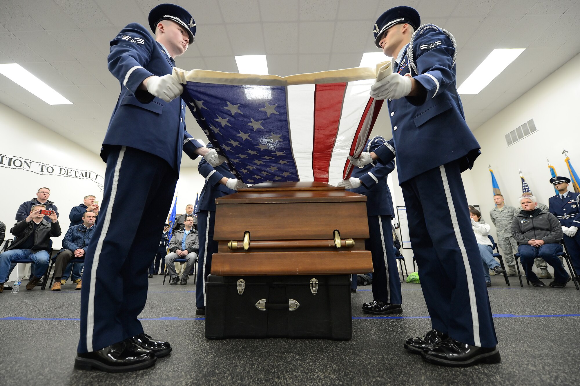 Airmen from the 436th Mission Support Group Base Honor Guard, conduct a ceremonial flag-folding over a training casket as a group of Honorary Commanders look on during a tour March 18, 2015, on Dover Air Force Base, Del. In the foreground are Senior Airman Gene Kellenberger, left, and Airman 1st Class Michael Laity. Honorary Commanders took part in a tour of the 436th MSG to better understand the important missions performed within the group and subordinate squadrons. (U.S. Air Force photo/Greg L. Davis)