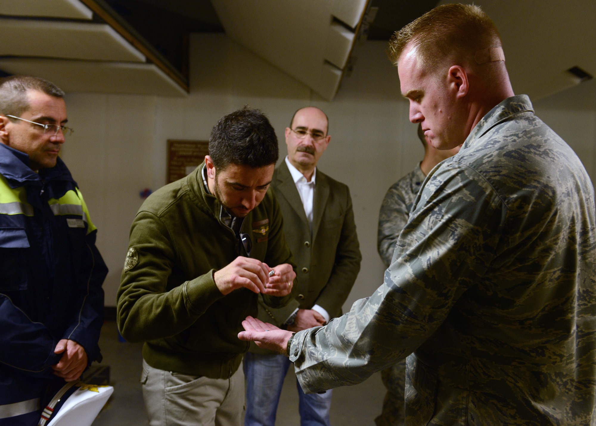 U.S. Air Force Capt. Brian Hess, 31st Security Forces Squadron logistics and resources officer in charge, displays a non-lethal training ammunition to local Italian police officials, March 20, 2015, at Aviano Air Base, Italy. During a tour, Aviano Polizia members and the Venice Polizia K-9 unit visited the 31st SFS armory, indoor firing range and the military working dog section. (U.S. Air Force photo by Airman 1st Class Deana Heitzman/Released)