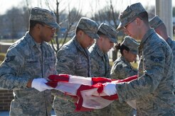 The base honor guard folds a U.S. Flag during a retreat ceremony in front of the Jones Building on Joint Base Andrews, Md., March 23, 2015. The flag was retired because its condition was no longer a fitting emblem for display. (U.S. Air Force photo/Airman 1st Class Ryan J. Sonnier)