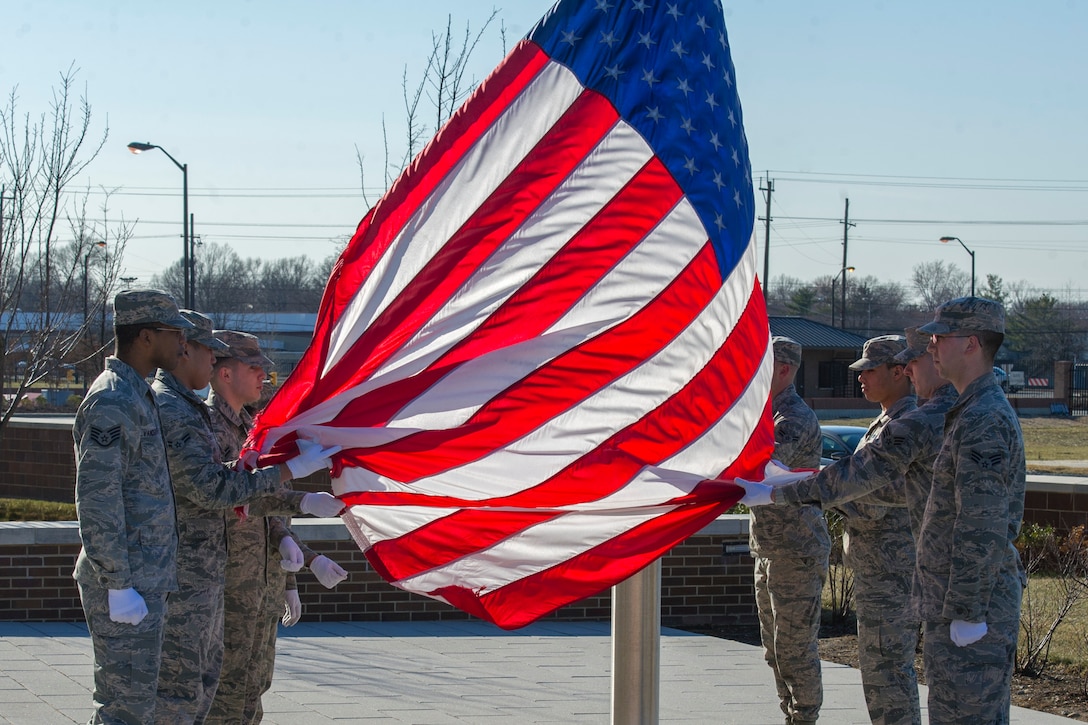 The Joint Base Andrews Honor Guard lowers a U.S. Flag during a retreat ceremony in front of the Jones Building, JBA, Md., March 23, 2015. The flag was retired because its condition was no longer deemed a fitting emblem for display. (U.S. Air Force photo/Airman 1st Class Ryan J. Sonnier)