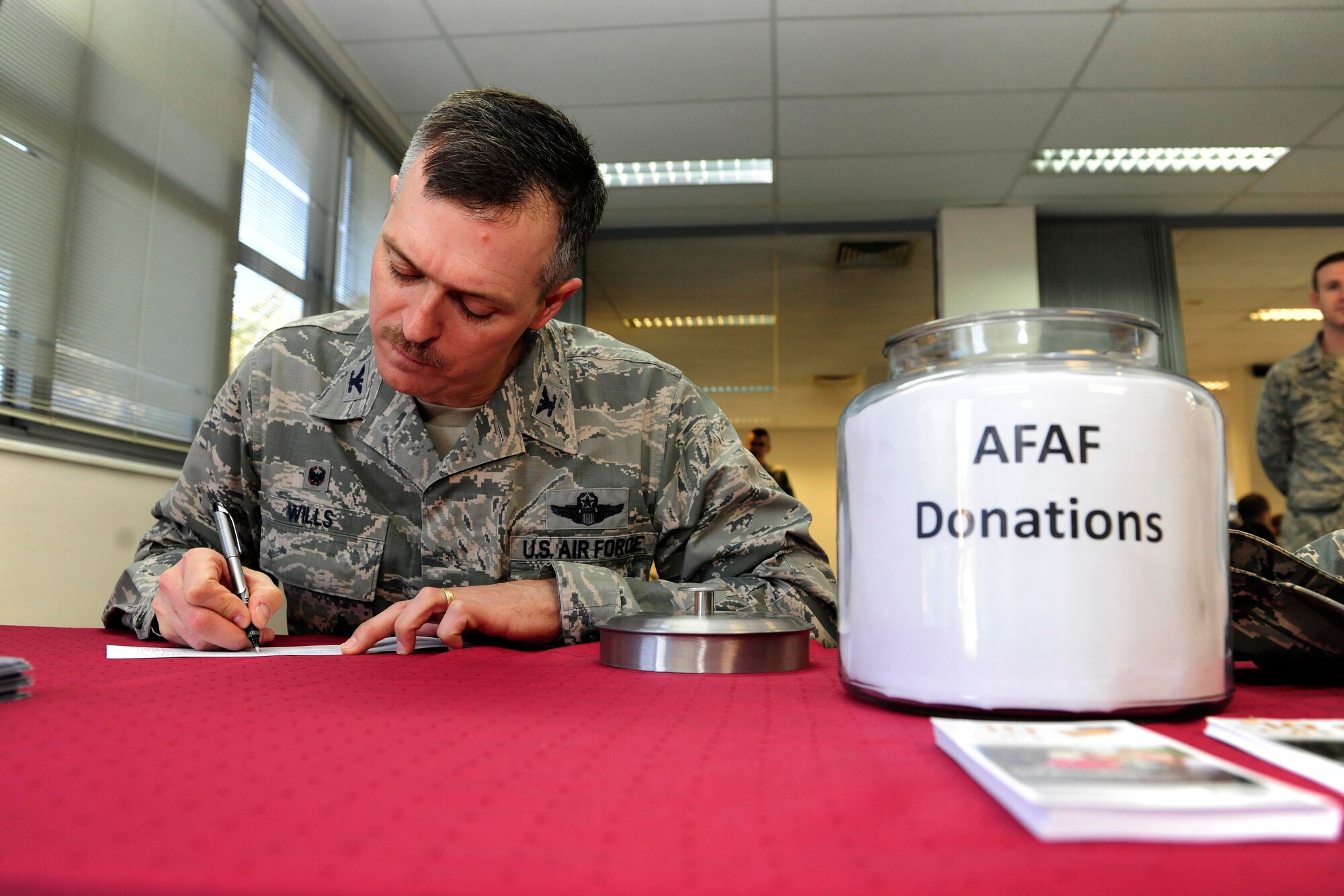 Col. Craig Wills, 39th Air Base Wing commander, makes a donation to the Air Force Assistance Fund March 24, 2015, at Incirlik Air Base, Turkey. The AFAF is an annual campaign that raises funds for charities that provide support to Air Force members in an emergency, with educational needs or a secure retirement home for widows or widowers of Air Force members in need of financial assistance. (U.S. Air Force photo by Senior Airman Krystal Ardrey/Released)