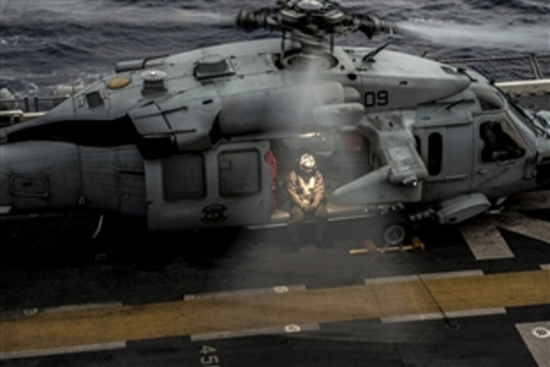 A U.S. sailor waits to takeoff on an MH-60S Seahawk helicopter on the forward-deployed amphibious assault ship USS Bonhomme Richard in the East China Sea, March 24, 2015. The sailor is a naval aircrewman assigned to Helicopter Sea Combat Squadron 25.