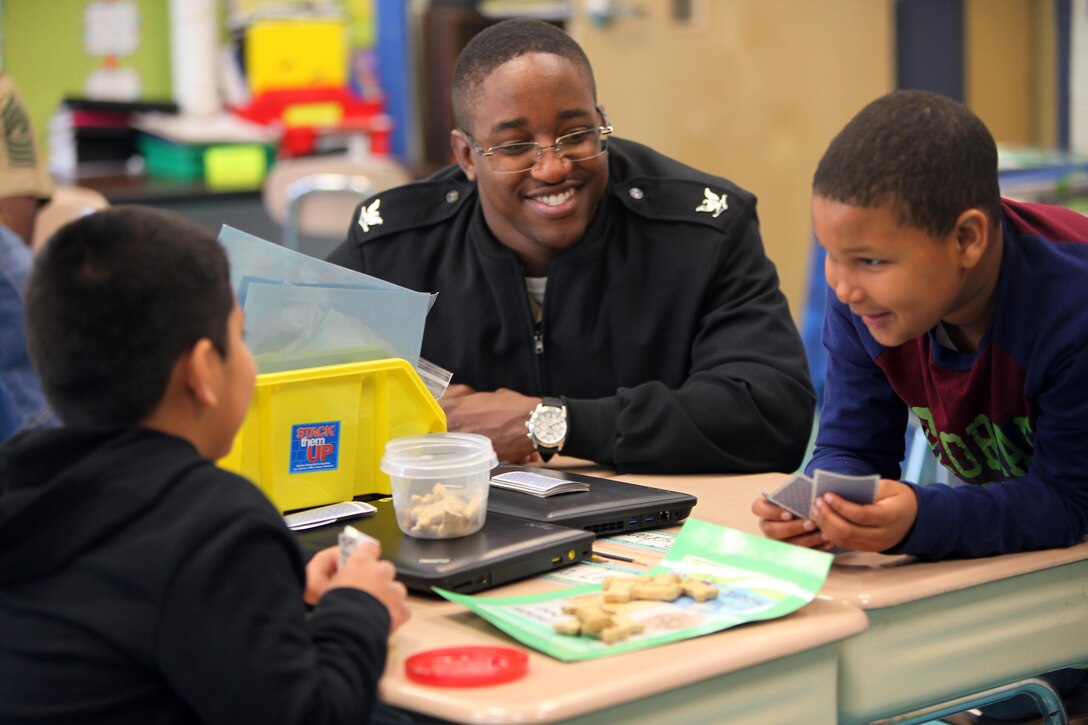 Petty officer 3rd Class Joshua Myers watches students play a math game at Arthur W. Edwards Elementary School in Havelock, N.C., March 13, 2015. Myers accompanied Marines and Sailors with Marine Wing Support Squadron 274 at Marine Corps Air Station Cherry Point, N.C., as they help the students learn to read, write and do math problems at the school. The service members visited the school to interact with the students on an academic level and show them a different side to the Marine Corps. Myers is a religious program specialist with MWSS-274.