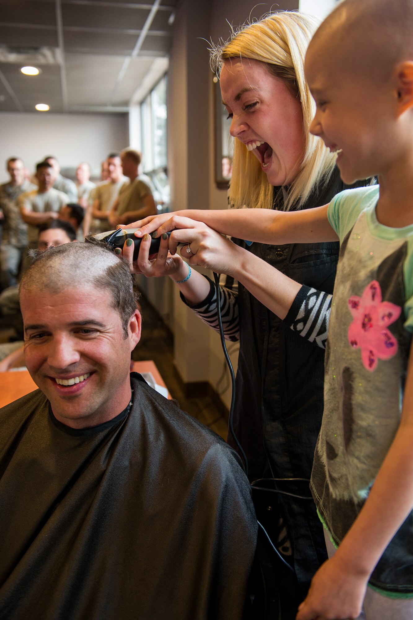 Maj. Nathan Litz, 419th Fighter Wing chief of safety, gets his head shaved with help from his daughter, Gracie, who is undergoing chemotherapy to battle lymphoblastic lymphoma. (U.S. Air Force photo/R. Nial Bradshaw)
