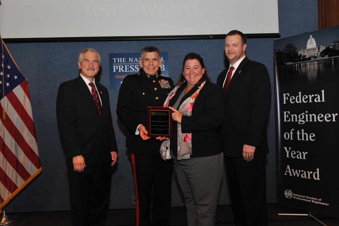 Megan Blucher, second from the right, engineering branch manager, Marine Corps Air Station Miramar, Calif., stands with Harve Hnatiuk, left, president of the National Society of Professional Engineers, Maj. Gen. Juan Ayala, second from the left, commanding officer of Marine Corps Installations Command, Headquarters Marine Corps, and David Scott Wolf, right, NSPE board member, as she holds her Federal Engineer of the Year Award as the Marine Corps’ top engineer in 2014, after a ceremony in Washington, D.C., Feb. 26. During her time on the air station, she has managed a team engineers and engineering technicians that handle the major maintenance and sustainment of the facilities.